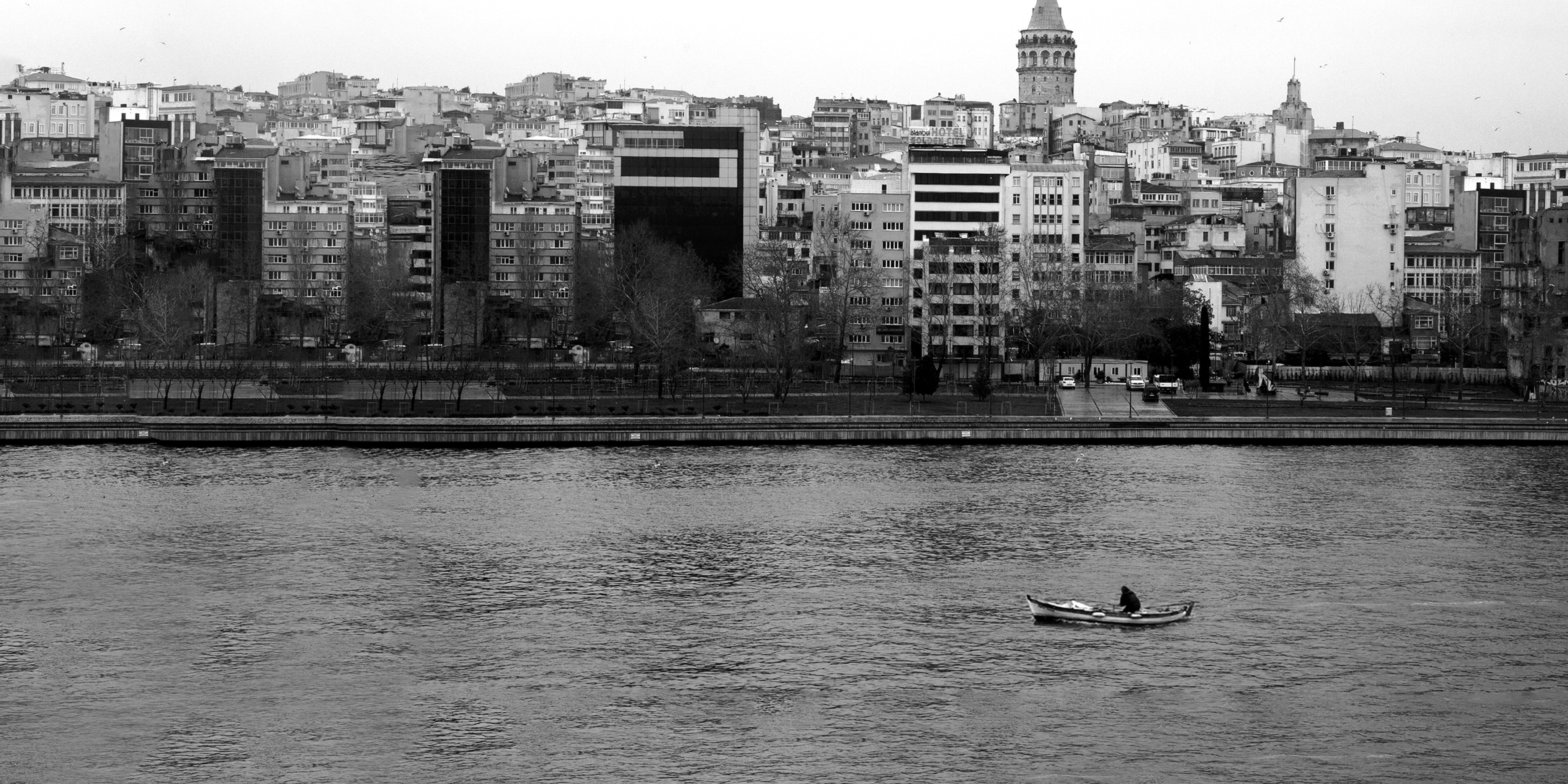 Person on a boat in the water next to a city
